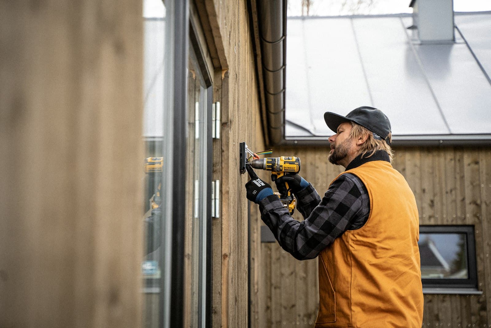 Artisan qui perce un bardage bois
